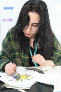Student painting a sun and flower design on a bag